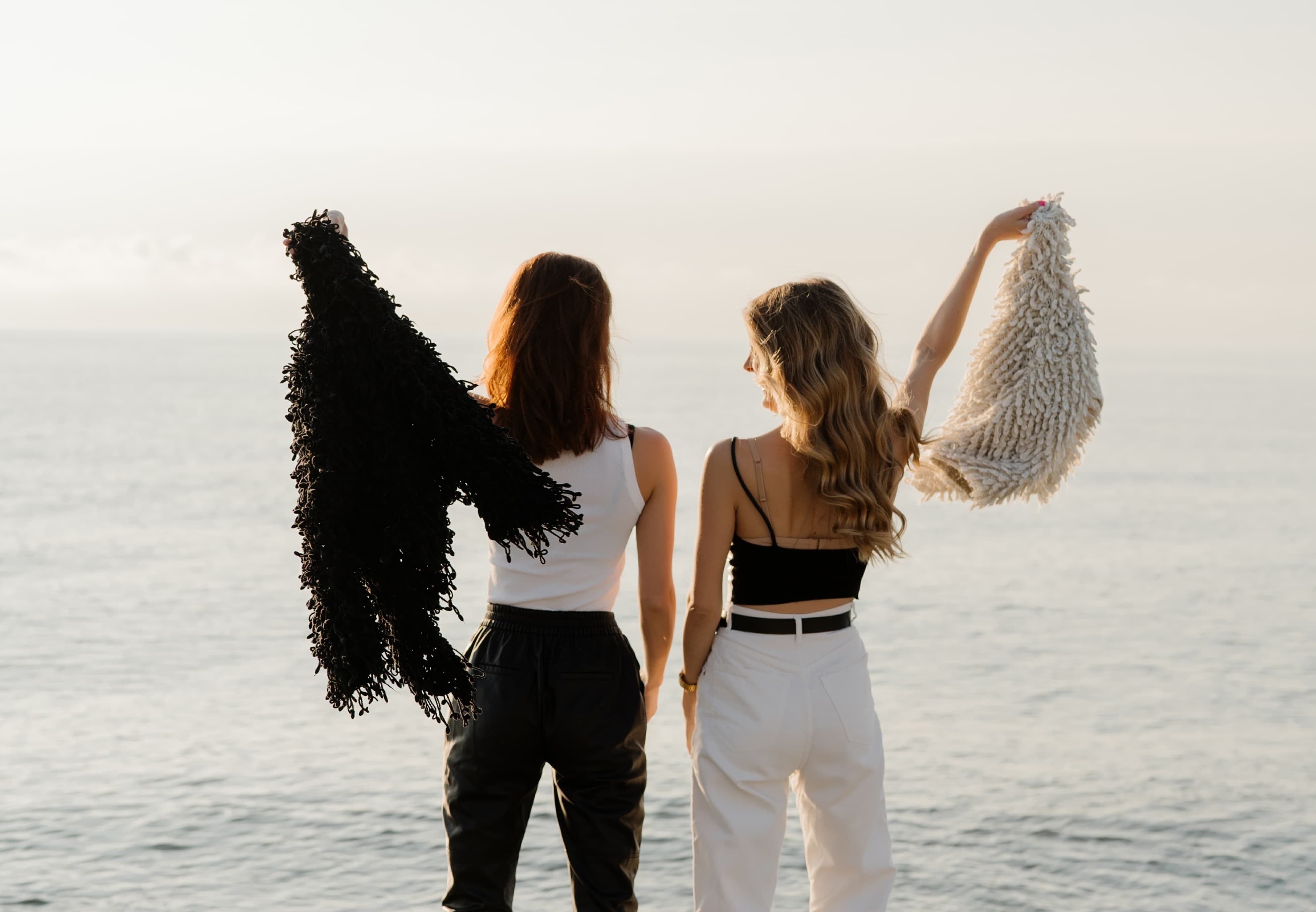 Two young women celebrating together with their hands raised on a sunny day